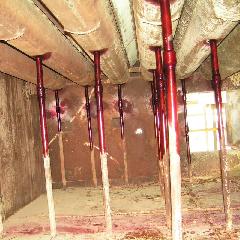 Piping under the HRSG, stained with penetrant dye for weld inspection, undergoing visual HRSG examination