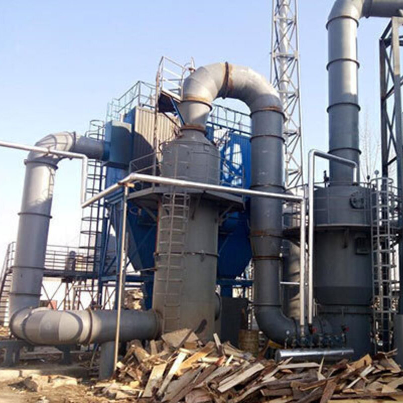 dust collection or filtration system. It includes large metal pipes, a tall cylindrical structure, and a hopper at the bottom. There are ladders and railings for access, and a pile of wood scraps or debris is visible on the ground nearby. The equipment appears to be part of a processing facility, possibly for woodworking or manufacturing.