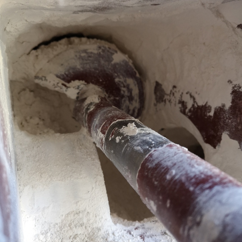 Inside the dosing device, visible hydrated lime and a screw conveyor in red-brown color. The side walls are covered with loose hydrated lime